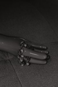 Kaboompics - Close-Up Pearl Link Bracelet on a Sculptural Jewelry Hand Against Dark Fabric