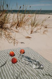 Kaboompics - Peaches and Glass Bottle on a Striped Towel by the Sea