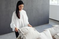 Kaboompics - Woman Fluffing Pillows on a Linen Sofa