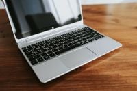 Kaboompics - Open Silver Laptop Angled Across a Wooden Table with Soft Background