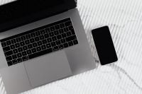 Kaboompics - Black Smartphone Beside a Silver Laptop on White Ribbed Marble, Modern Tech Flat Lay