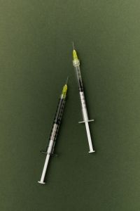 Kaboompics - Two Green Needle Syringes on Green Background