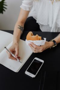 Kaboompics - Freelancer Taking Notes While Holding a Burger