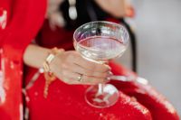 Kaboompics - Woman Holding Champagne in Red Suit, Seated Party Portrait