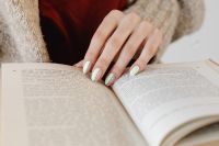 Kaboompics - Woman Holding a Polish Art Book in a Cozy Knit Sweater for Reading Campaigns