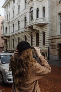 Kaboompics - Woman Adjusting a Black Cap on a Historic City Street
