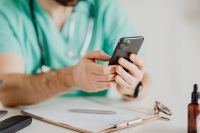 Kaboompics - Doctor Holding Smartphone Above Medical Clipboard