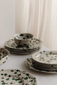 Kaboompics - Stacked Green Splatter Dinnerware against a Soft Curtain Background