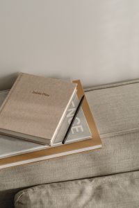 Kaboompics - Planner and Pencil on Stacked Books with Neutral Sofa Copy Space
