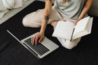 Kaboompics - Woman Working on a Laptop with an Open Planner at Home