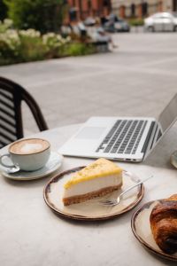 Kaboompics - Laptop and Cake with Coffee on a City Cafe Table