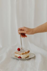 Kaboompics - Hand Reaching with a Fork Toward Raspberry-Topped Napoleonka Cake