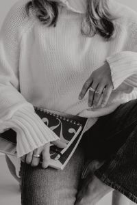 Kaboompics - Black and White Faceless Woman in White Sweater with Rings and Architecture Book