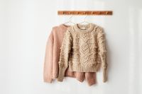 Kaboompics - Blush and Cream Sweaters on Wooden Wall Rack