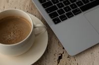 Kaboompics - Coffee Cup and Open Laptop on Travertine Table From Above
