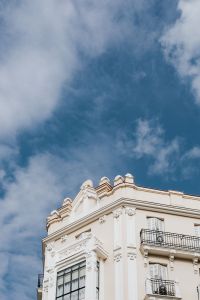 Kaboompics - Vertical Low-Angle View of Ornate Madrid Facade and Sculpted Roofline Against Clouds