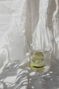 Kaboompics - Two Clear Glasses of Water and Lime Water on Sunlit White Linen, Minimal Drink Styling