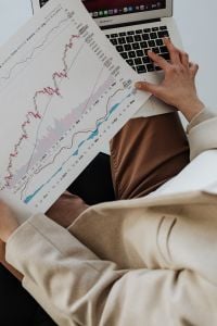 Kaboompics - Hands Reviewing Printed Graphs beside a Laptop