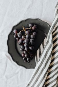 Kaboompics - Overhead Black Grapes on a Dark Plate with Striped Linen, Simple Food Styling