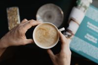 Kaboompics - Hands Holding Coffee Cup Over a Magazine