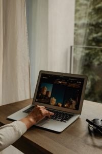 Kaboompics - Hand Browsing City Photos on Laptop by Window
