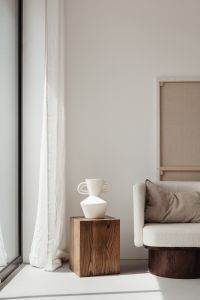 Kaboompics - White Sculptural Vase on Walnut Pedestal beside Cushioned Armchair