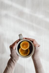 Kaboompics - Cup of Orange Tea Held Above a Beige Blanket
