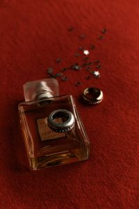 Kaboompics - Perfume Bottle with Star Confetti on Burgundy Background