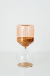 Kaboompics - Single Amber Glass Hourglass with Fine Sand Isolated Against a White Background