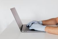 Kaboompics - Side View of Person Typing on Laptop in Protective Gloves