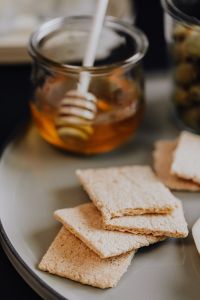 Kaboompics - Honey Dipper in Glass Jar with Crispbread, Warm Close-Up Healthy Snack Still Life
