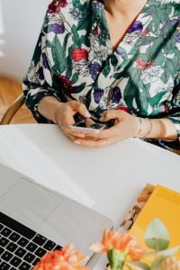 Kaboompics - Woman Texting on a Smartphone at a Laptop Workspace with Flowers
