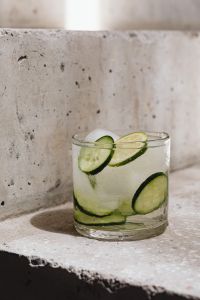 Kaboompics - Close-Up Cucumber and Lime Detox Water with Ice on a Concrete Ledge, Minimal Summer Drink Still Life