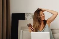 Kaboompics - Woman Adjusting Her Hair While Holding a Smartphone on the Sofa
