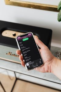 Kaboompics - Black speaker on marble table, white wall, mobile phone in hand