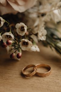 Kaboompics - Gold Wedding Rings with White Waxflower on Neutral Fabric