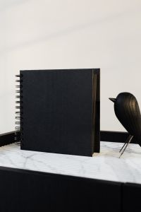 Kaboompics - Close-Up of Black Notebook and Wooden Bird Decor on a Marble Table