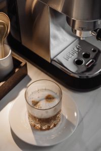Kaboompics - DeLonghi Espresso Machine with Cappuccino Glass, Home Coffee Bar Close-Up