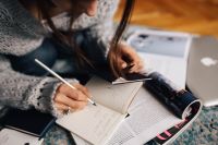 Kaboompics - Woman in a grey sweater taking notes in an organizer