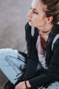 Kaboompics - Blonde woman in a black jacket and ripped jeans by a green handrail