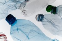 Kaboompics - Crushed Plastic Bottles with Blue and Green Caps on White, Recycling and Microplastic Pollution Concept