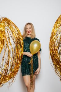Kaboompics - Woman Holding a Gold Balloon Among Metallic Streamers