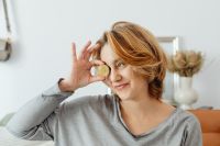 Kaboompics - Smiling Woman Holding Bitcoin Coin Beside Her Eye