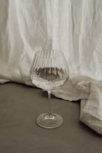 Kaboompics - Clear Water in a Stemmed Ribbed Glass Against Soft Linen