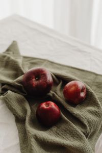 Kaboompics - Whole Red Apple and Halved Fruit on a Round Wooden Serving Board, Rustic Food Styling