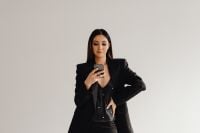 Kaboompics - Asian Businesswoman Checking a Smartphone in a Black Suit
