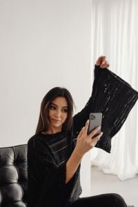 Kaboompics - Woman Holding a Smartphone and Adjusting Her Hair in a Leather Chair