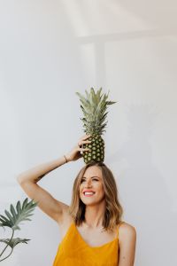Kaboompics - Woman Posing with Pineapple Overhead beside Green Houseplant, Minimal White Background