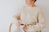 Kaboompics - A woman in a warm sweater drinks tea