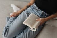 Kaboompics - Relaxed Woman Reading an Open Book on a Neutral Sofa